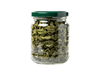 Glass jar filled with dried green herbs, closeup