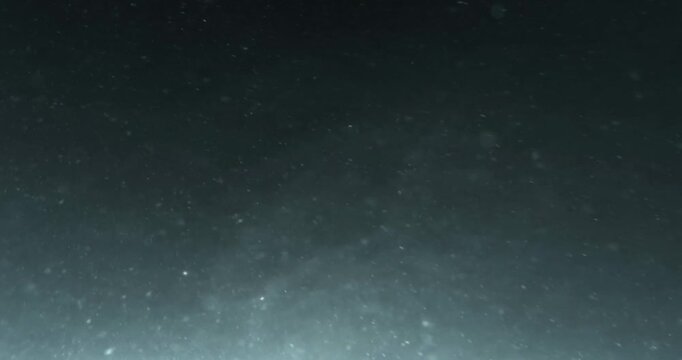 Real 4K underwater footage of illuminated marine snow and drifting plankton, shimmering dust and light rays moving through deep ocean water, creating a mesmerizing atmospheric marine background. 