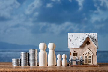 Wooden house toy model, stack of coins and figures of people on nature background. Concept of planning to save money for purchase or construction of a home, mortgage and real estate investment