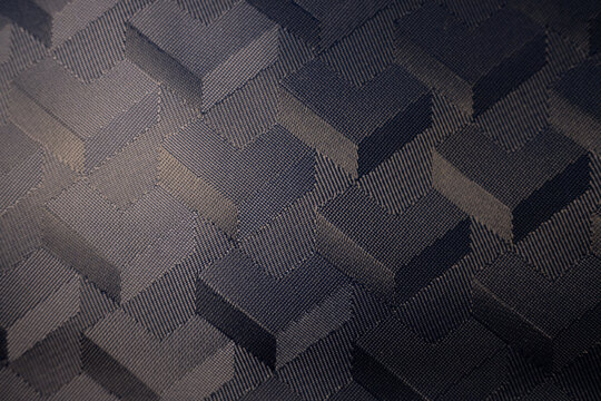 Macro of a dark woven textile with a 3D geometric cube pattern. A modern, abstract background with a sophisticated, high-tech feel and an optical illusion effect.