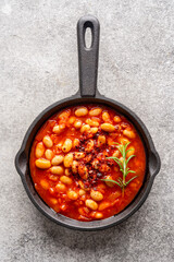 Baked bean dish in cast iron pan on vintage background. 
