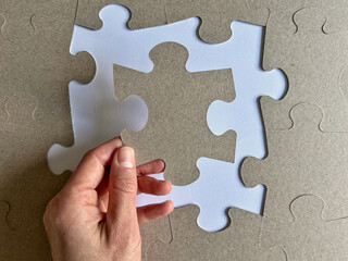 A hand holding a large white puzzle piece represents searching for the missing key element, understanding boundaries, and completing an important personal structure