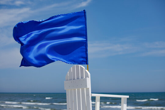 Blue flag waving on top of lifeguard chair, rescuer observation point on the beach