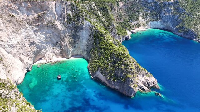 Aerial drone video of famous steep white rocky cliffs creating beautiful coves and turquiose sea caves of Kampi visited by small boats and yachts in northern part of Zakinthos island, Ionian, Greece