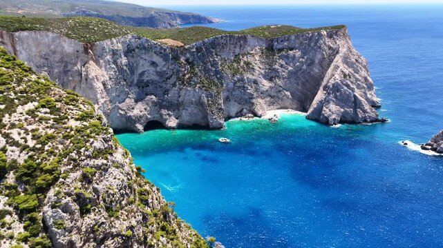 Aerial drone video of famous steep white rocky cliffs creating beautiful coves and turquiose sea caves of Kampi visited by small boats and yachts in northern part of Zakinthos island, Ionian, Greece
