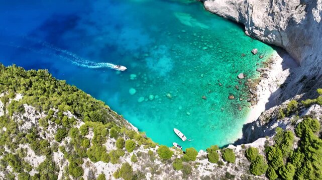 Aerial drone video of famous steep white rocky cliffs creating beautiful coves and turquiose sea caves of Kampi visited by small boats and yachts in northern part of Zakinthos island, Ionian, Greece