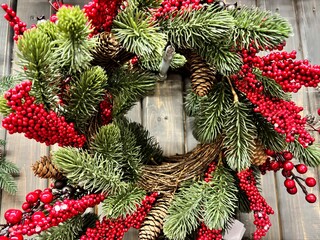 Christmas wreath with pine branches and red berries on wooden door