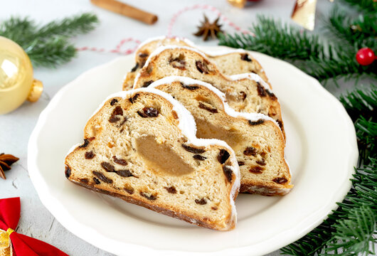 Christmas marzipan stollen with raisins, powdered sugar on white background. Christmas food. 