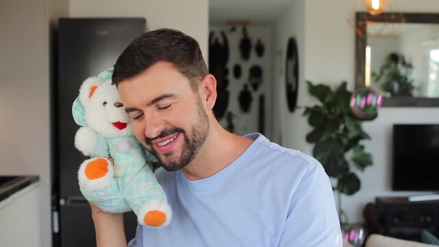 Cute adult man holding a teddy bear and making  soap bubbles 