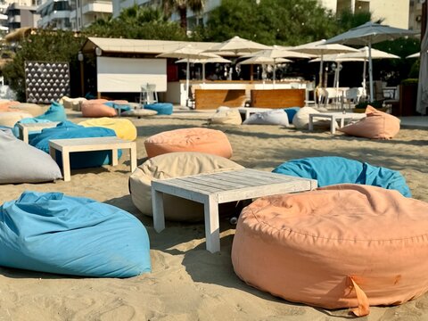 vue sur une terrasse d'un bar d'albanie avec des poufs et table dans le sable un jour ensoleill&eacute; d'&eacute;t&eacute;