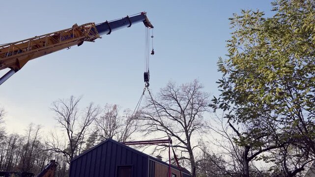 A modular house is lifted by a truck crane.