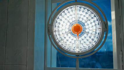 An overhead surgical light illuminates a sterile operating room, showcasing its intricate design. The bright lights reflect a commitment to precision and safety in medical procedures.