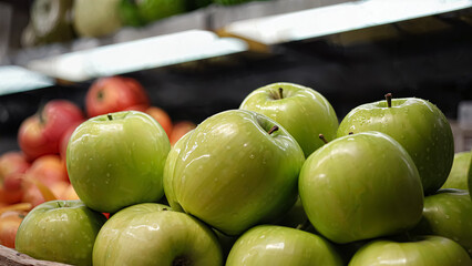 A vibrant pile of fresh green apples is showcased at a grocery store, highlighting their shiny skin and crisp appearance. Positioned among other colorful fruits, they invite a healthy choice.