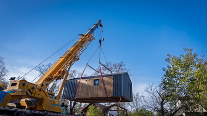 A house is being lifted with the help of a truck crane's boom.