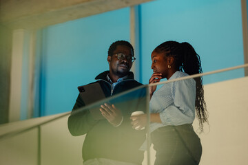 Colleagues discussing project with tablet and coffee