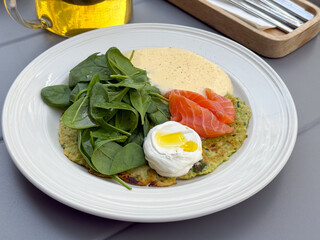 Closeup of brunch plate with poached egg, salmon, and spinach. Healthy breakfast, nutrition balance, and fresh cuisine concept.