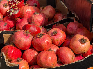 Fresh pomegranates displayed in boxes at street market. Organic fruit, local agriculture, and vibrant color of seasonal harvest.