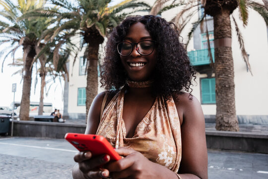 Black woman smiling using smartphone in Canary Islands holidays enjoying summer