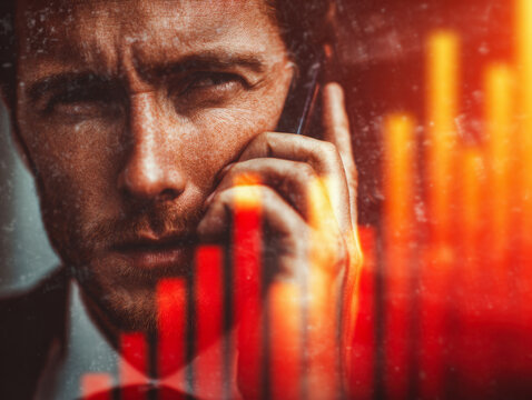 Focused businessman holding smartphone with intense expression and glowing financial chart reflections overlay in warm tones for economic concept - Powered by Adobe