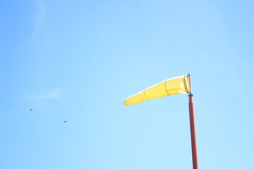 Yellow Windsock Blowing Under Clear Skies