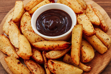 Crispy potato wedges served with rich dipping sauce on a wooden plate