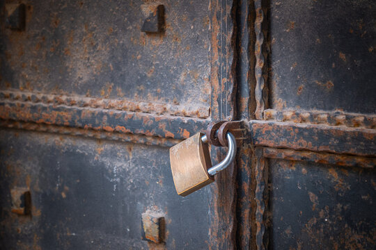 Old and rusty metal door. Locked with a padlock.