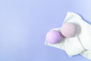 Soft pastel bath bombs resting on a white towel against a light purple background