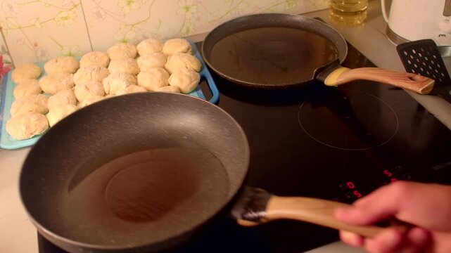 caucasian food blogger preheats pan on stove and tests oil with spatula, step-by-step kitchen footage with tray of raw