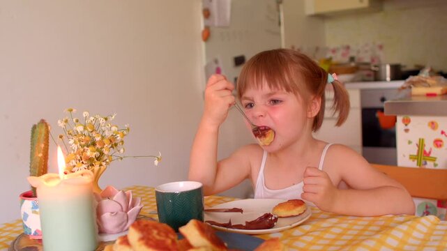 little white girl at breakfast stirring spoon, tasting jam, rubbing forehead, contemplative pause, slow bite