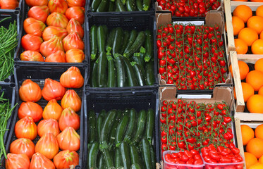 boxes of harvest being sold at the vendors stand displaying ripe tomatoes summer squash and crisp pole beans