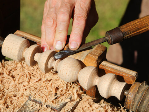 Elderly artisan fingers processing wooden piece with lathe and chisel tool - Powered by Adobe
