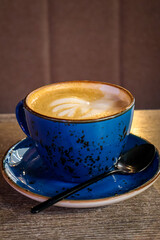 Cup of cappuccino on a wooden table in a cozy café. Warm natural light and relaxing morning atmosphere. 