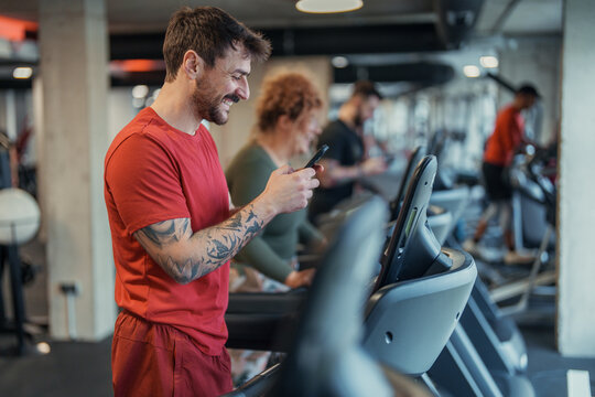 Indoor gym workout with two adults exercising on treadmills featuring focused male and female athletes - Powered by Adobe