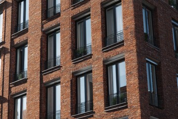Obraz premium Modern brick apartment building with large windows and balconies located in an urban setting during bright daylight hours