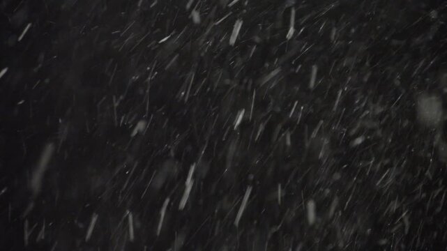 Intense Real Snowfall Overlay On Black Background With Fast-Flying Snowflakes Blown By Strong Wind, Creating A Dramatic Winter Blizzard Effect For Video And Film Projects.
