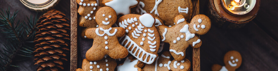 Traditional holiday homemade gingerbread cookies in a vintage wooden box. Craft paper with Christmas word on it. Festive mood, cozy home atmosphere, handmade toys, fir tree branches