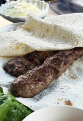 Fried meat sausages with lavash and herbs, a traditional Uzbek dish.