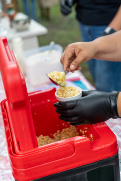 Traditional Mexican esquite in a cup, with cooked corn kernels, cream, and cheese, at a street stall in a garden. chascas, vasolotes, trolelotes, elote en vasito, elote en vaso
