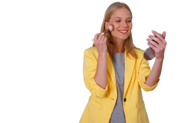 Young woman smiling, applying blush to her cheek with a makeup brush, holding a compact mirror for her beauty routine