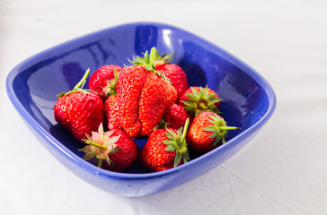 Strawberries Overflowing From Blue Bowl on White Tablecloth