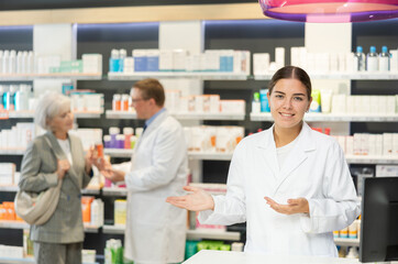 Obraz premium Young female pharmacist in medical uniform posing while working in pharmacy