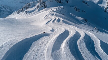 Aerial view of curved ski tracks in deep snow on mountain slopes. Winter sports freeride skiing and alpine landscape photography concept.