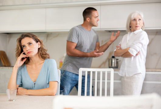 Elderly woman gets angry during quarrel with man and woman couple in kitchen