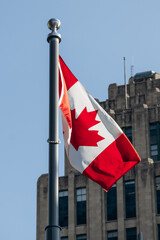 Montreal, Canada - August 11, 2025: Canadian flag waving in front of the historic Aldred Building...