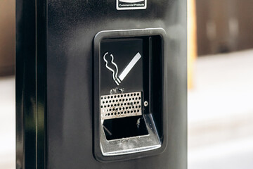 Outdoor metal ashtray and cigarette disposal bin with smoking sign in Montreal, Canada