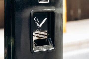 Outdoor metal ashtray and cigarette disposal bin with smoking sign in Montreal, Canada