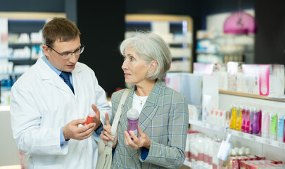 Male pharmacist gives advice to a mature woman on what product intimate hygiene to buy for personal...
