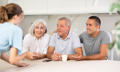 Young married couple and senior parents talk about home life