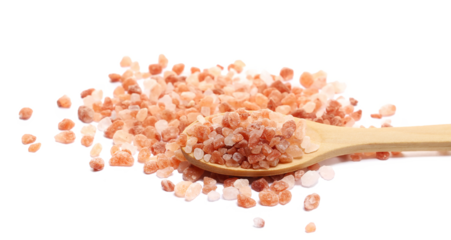 Himalayan salt grains pile in wooden spoon isolated on white background, side view