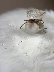 Small Linen Bag Filled with Crystals on White Fur with Beige Background